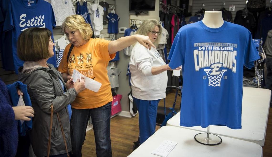 Brenda Flynn, center, talks to Charlotte Richardson, left, as they stand in line to buy Estill County’s 14th Region Basketball Championship T-shirts, Friday afternoon, March 9, 2018.