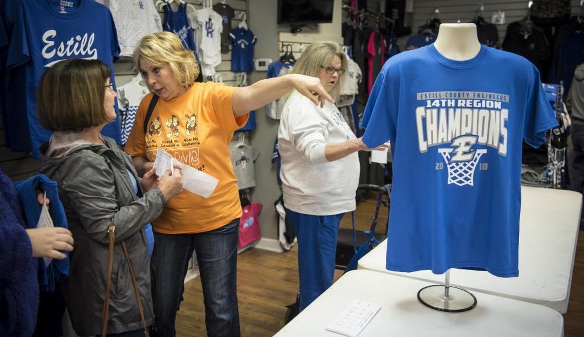 Brenda Flynn, center, talks to Charlotte Richardson, left, as they stand in line to buy Estill County’s 14th Region Basketball Championship T-shirts, Friday afternoon, March 9, 2018.