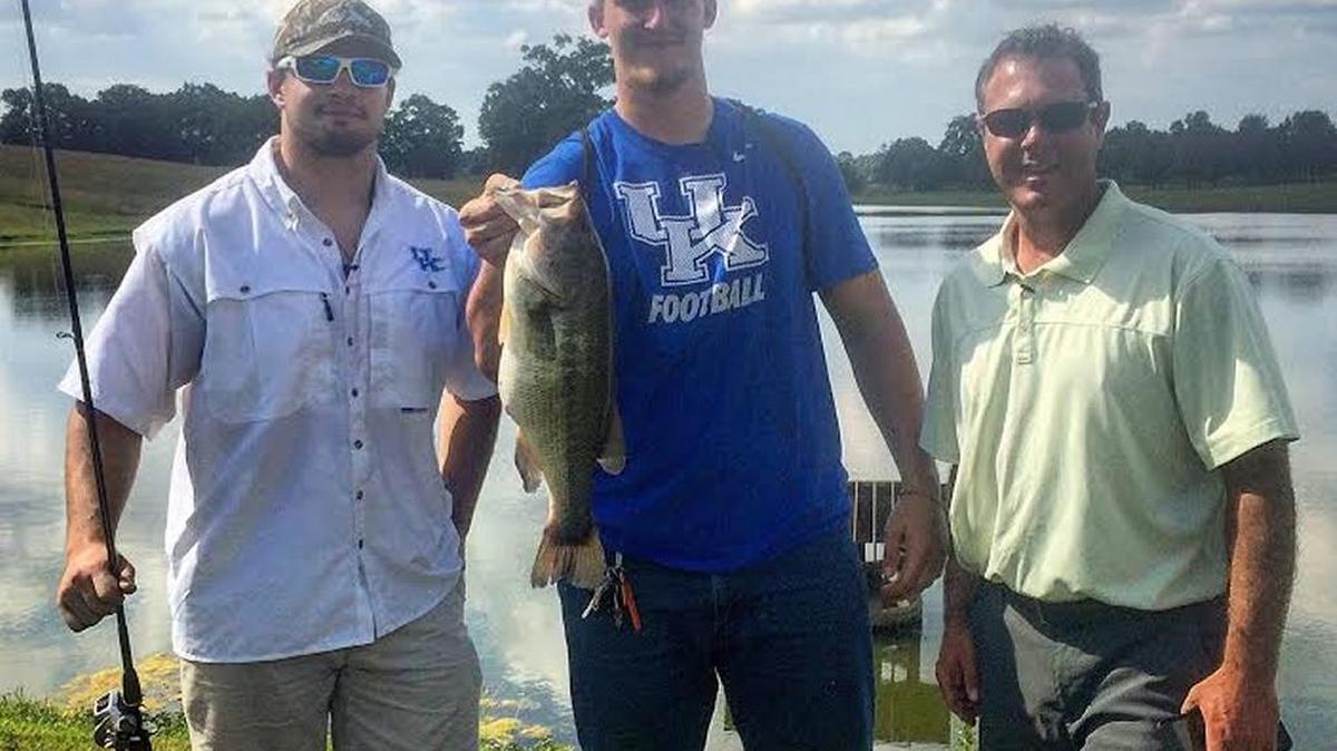 UK football players Kash Daniel, left, and Landon Young, with fish, stood with Chad Miles, host of the KET’s outdoors television program “Kentucky Afield.”