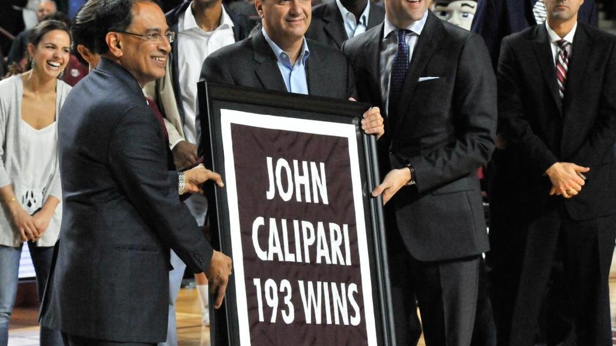 Former Massachusetts basketball coach John Calipari, center, flanked by UMass Chancellor Kumble Subbaswami, left, and Athletic Director Ryan Bamford, during a banner-raising ceremony honoring the former coach Wednesday, Dec. 16, 2015, at the Mullins Center at UMass in Amherst, Mass.