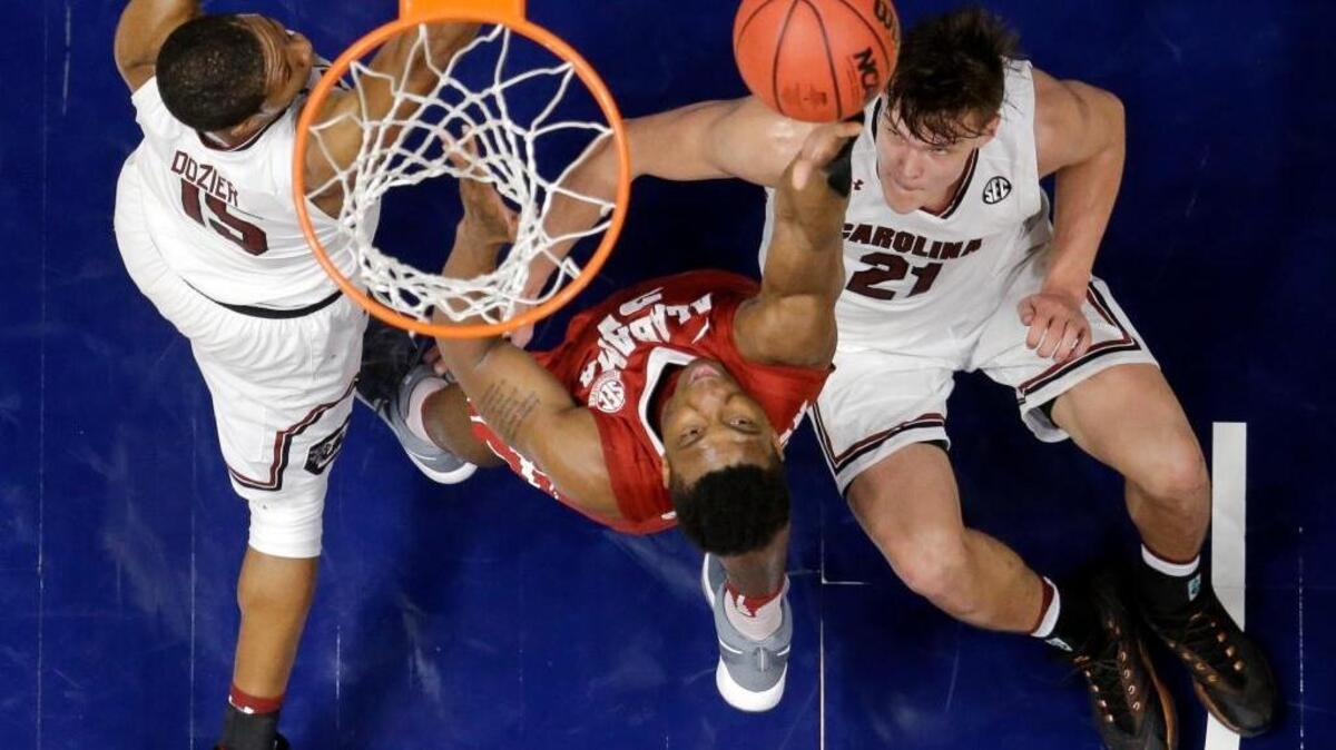 Alabama forward Bola Olaniyan, center, shoots over South Carolina guard PJ Dozier (15) and Maik Kotsar (21) during the first half of the Crimson Tide’s 64-53 win over South Carolina in the Southeastern Conference tournament Friday, March 10, 2017, in Nashville, Tenn.