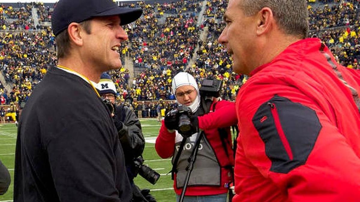 Michigan head coach Jim Harbaugh, left, greets Ohio State head coach Urban Meyer on the Michigan Stadium field before last year’s Michigan-Ohio State game in Ann Arbor, Mich. Michigan visits Ohio State this year with both teams looking for an invitation to the College Football Playoff.