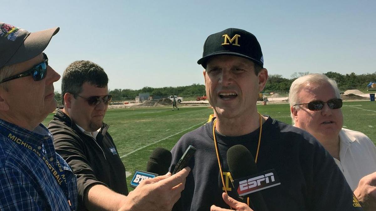 In this Feb. 29, 2016, file photo, University of Michigan NCAA college football head coach Jim Harbaugh speaks to reporters at IMG Academy in Bradenton, Fla. The NCAA announced Friday, April 8, 2016, that it was barring football coaches from holding camps or clinics on other campuses, siding with the Southeastern Conference in its high-profile dispute with Michigan's Jim Harbaugh.