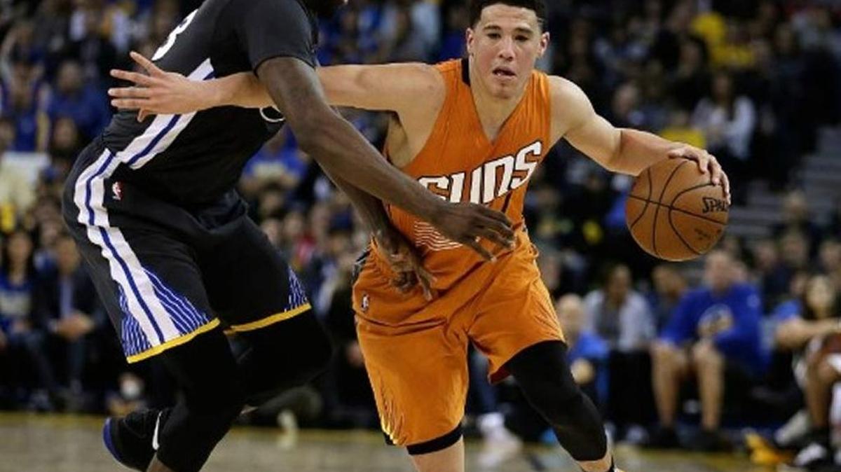 Phoenix Suns' Devin Booker, right, drives the ball against Golden State Warriors' Draymond Green during the second half of an NBA basketball game Saturday, March 12, 2016, in Oakland, Calif.